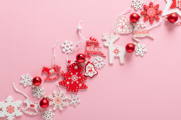 Christmas composition with red and white Christmas tree eco-toys in the center diagonally on a light pink background.