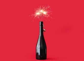 Champagne bottle with burning Christmas sparklers on color background