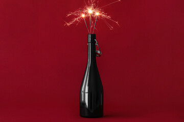 Champagne bottle with burning Christmas sparklers on color background