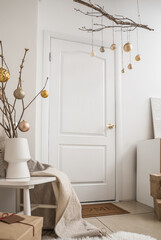 Tree branches with Christmas balls hanging near white door in room