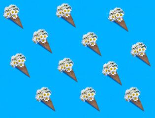 Ice cream cone with white chamomile on the blue background. Pattern. Flat lay. Top view.