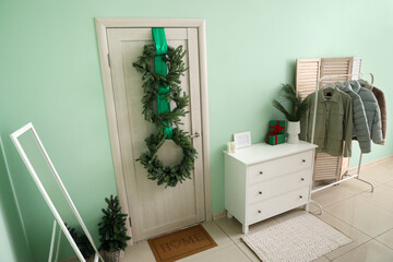 Interior of hall with wooden door, Christmas wreaths and jackets