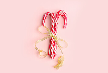 Sweet candy canes tied with ribbon on pink background