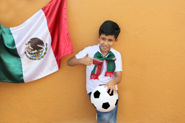8 year old latino boy is excited to see the mexican soccer team with his ball and mexico flag ready for the game
