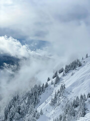 Remains of snowfall clouds rolling across freshly snow-covered mountainside