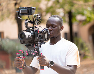 giovane ragazzo Cameraman con cinepresa digitale sulla spalla che riprende un scena all'aperto