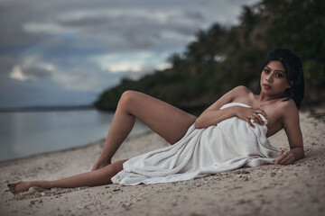 pretty girl covered only with a towel on the beach in the evening