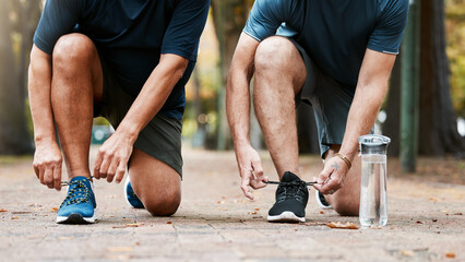 Fitness, run and men friends tying their shoes while doing an outdoor cardio workout in the city....