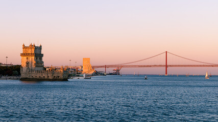 Panorama of Belém in Lisbon, the capital of Portugal. Sunset over Tagus river. Cityscape with Torre de Belém, Belém Tower and red iconic 25 de Abril Bridge, 25th of April Bridge. - obrazy, fototapety, plakaty