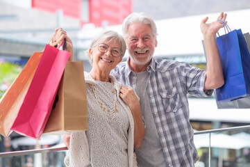 Cheerful caucasian senior couple carrying shopping bags enjoying shopping, consumerism sales...