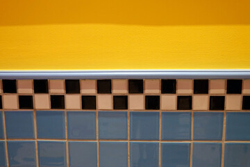 Detail of a blue and yellow ceramic tile wall in the bathroom