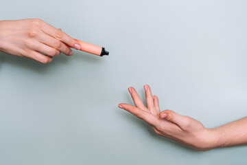 Transferring vape from one hand to another against light background.