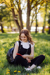 Obraz premium Photo of a positive cheerful teenage girl spends time in the park and using mobile phone.