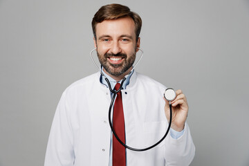 Male doctor smiling happy cheerful man wears white medical gown suit use stethoscope look camera work in hospital isolated on plain grey color background studio portrait. Healthcare medicine concept.