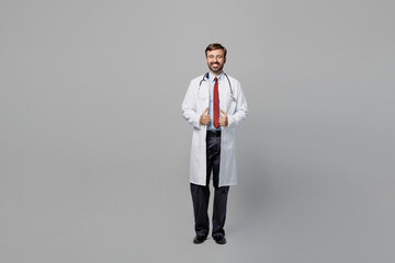 Full body male doctor confident cheerful smiling man wearing white medical gown suit work in...