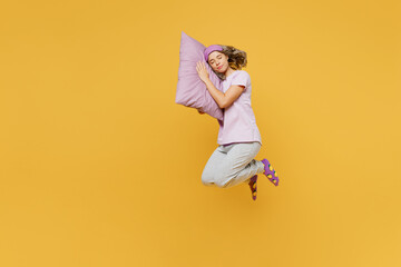 Volledige lichaam zijwaarts jonge vrouw dragen paarse pyjama jam slaap oogmasker rust ontspannen thuis spring hoog zet hoofd op kussen sluit ogen geïsoleerd op effen gele achtergrond studio portret. Nachtdutje concept.
