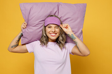 Calm young woman she wears purple pyjamas jam hold sleep eye mask pillow behind head look aside...