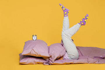 Full body young woman wears purple pyjamas jam sleep eye mask rest relax at home lying on bed duvet...