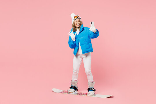 Snowboarder fun woman wear blue suit goggles mask hat ski padded jacket do selfie shot mobile cell phone isolated on plain pastel pink background Winter extreme sport hobby weekend trip relax concept