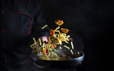 The chef prepares Thai food in the restaurant with fresh vegetables and spiced pasta. The cook...