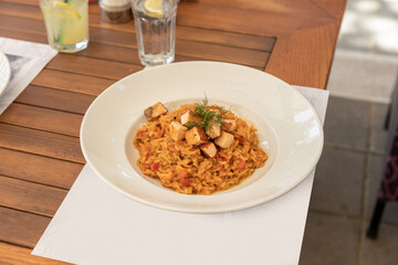 Risotto served in white plate on a restaurant table, top view