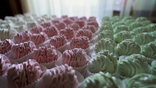 Many red, green and white cooked marshmallows lie on the table. Camera rotating