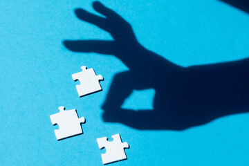 Shadow of ok sign near pieces of jigsaw puzzle. Concept of success
