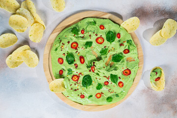 creamy avocado board with chili peppers, herbs and nachos Selective focus with blurred foreground and background