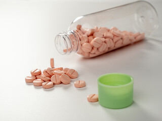 Bottle with pink pills on a white background. Medicine in tablets.