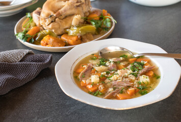 Plate with fresh cooked chicken noodle soup cooked with alphabet pasta on kitchen table