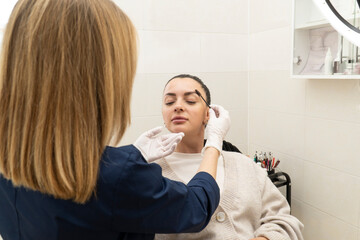The master sets the client's eyebrows with gel and a brush for fixing the eyebrows, does the...