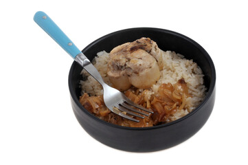 Paupiette de veau avec du riz et des oignons confits servis dans une assiette sur fond blanc