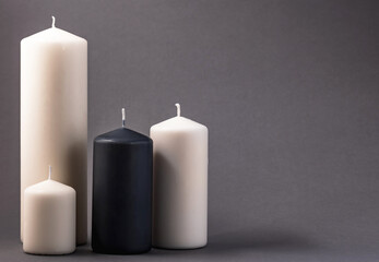 Fototapeta na wymiar Four different candles on a gray background.