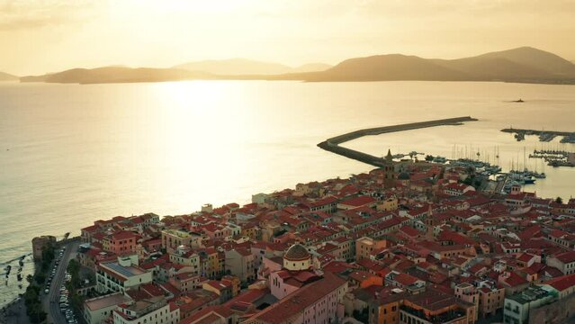 Picturesque view of sunset over the Old town of Alghero, Sardinia - Italy.
Flying over ancient Italian town towards the ocean at dusk.