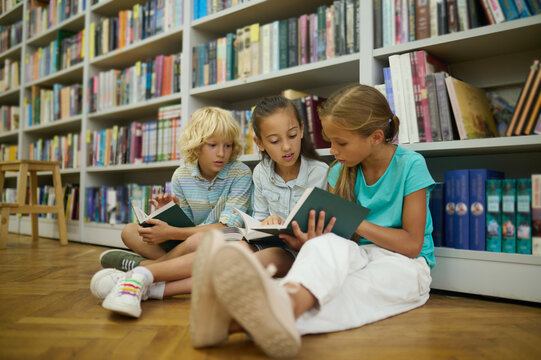 Group of kids reading while sitting on the floor in the library