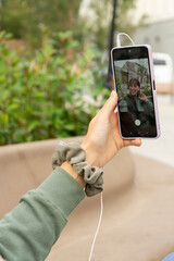 happy girl. Hand of a girl holding the cell phone while she takes a selfie in a square