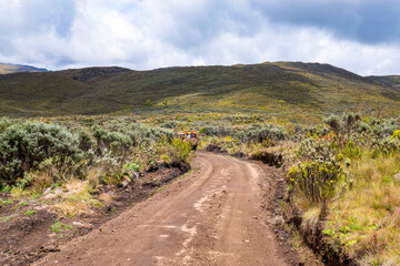 A safari van on a dirt road against a mountain background at Chogoria Route, Mount Kenya National Park, Kenya