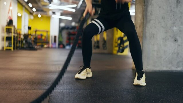 Woman athlete working out with battle rope in gym, endurance and heart health