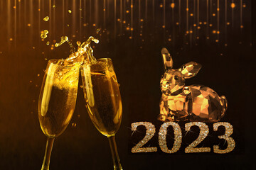 New Year 2023 golden rabbit symbol and two glasses of sparkling champagne tilted towards each other on a dark background.