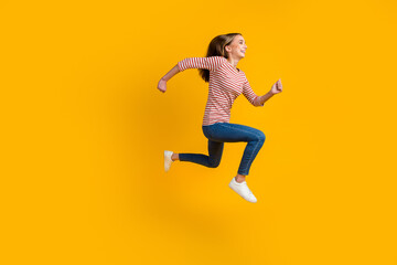 Fototapeta na wymiar Full side view of smiling cheerful young brunette woman jumping like running isolated on bright color background
