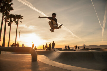 Teenage boy skating at skatepark during sunset