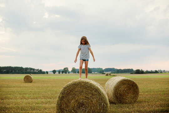 Girl standing on hay bale