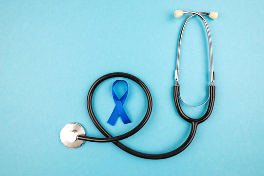 Top view photo of stethoscope and blue ribbon symbol of prostate cancer awareness on isolated pastel blue background