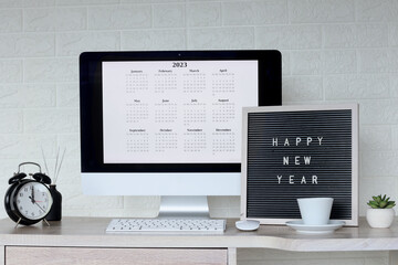 Happy New Year text on board with 2023 calendar on computer screen