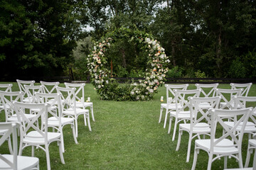 Wedding ceremony. Very beautiful and stylish roundwedding arch, decorated with various fresh flowers, standing in the garden.