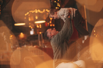 Candid authentic happy dad playing with little son fooling around at wooden lodge Xmas decorated