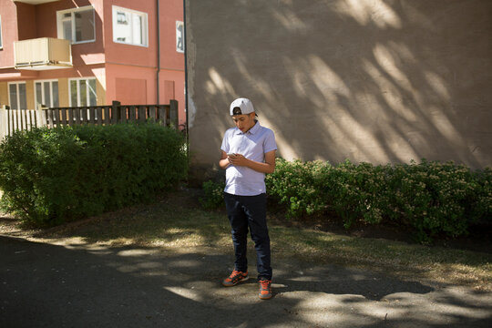 Boy in baseball cap using smartphone
