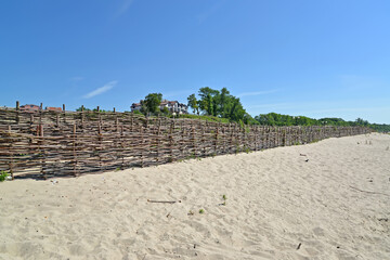 Fototapeta na wymiar Protective wicker fence along the sandy coast of the Baltic Sea. Yantarny village, Kaliningrad region