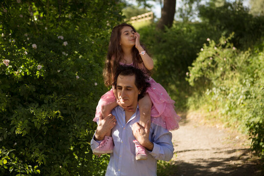 Man giving daughter piggyback ride in park