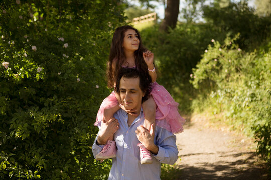 Man giving daughter piggyback ride in park